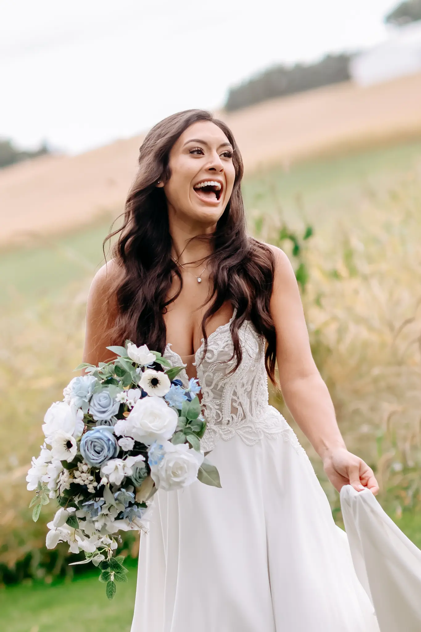 Bride walking with a bouquet through a grassy field in soft daylight