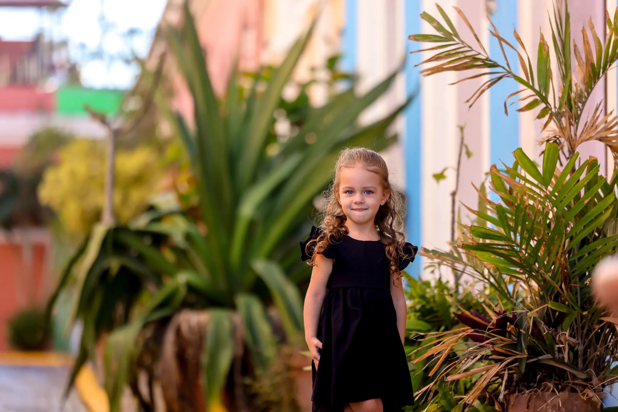 Young girl standing among lush tropical foliage in Puerto Rico, photographed by Olga Thomas