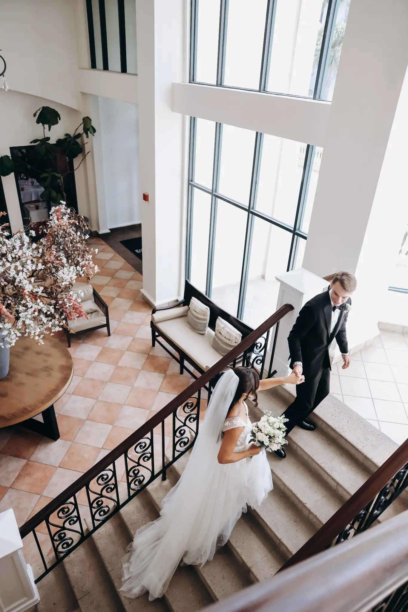 Bride and groom together on a grand staircase inside a historic building