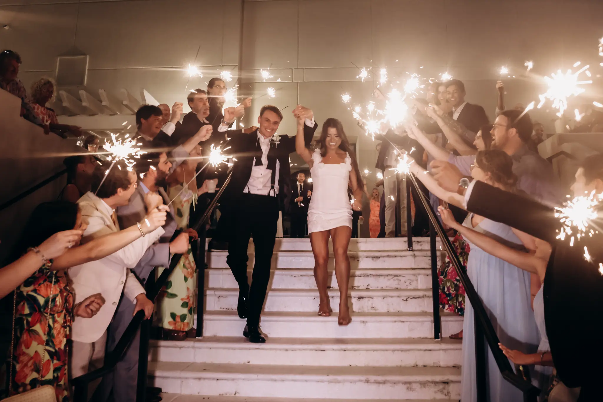 Bride and groom leaving through a sparkler send-off on a staircase