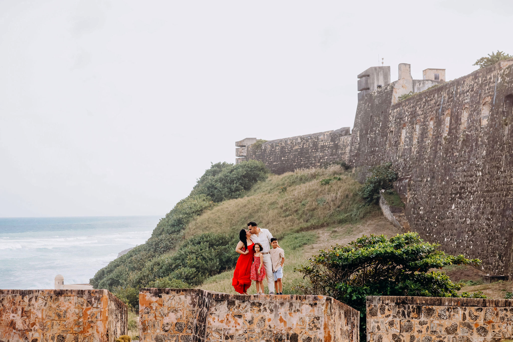 Family standing beside El Morro’s historic stone walls and ocean view in Old San Juan, Puerto Rico, photographed by Olga Thomas