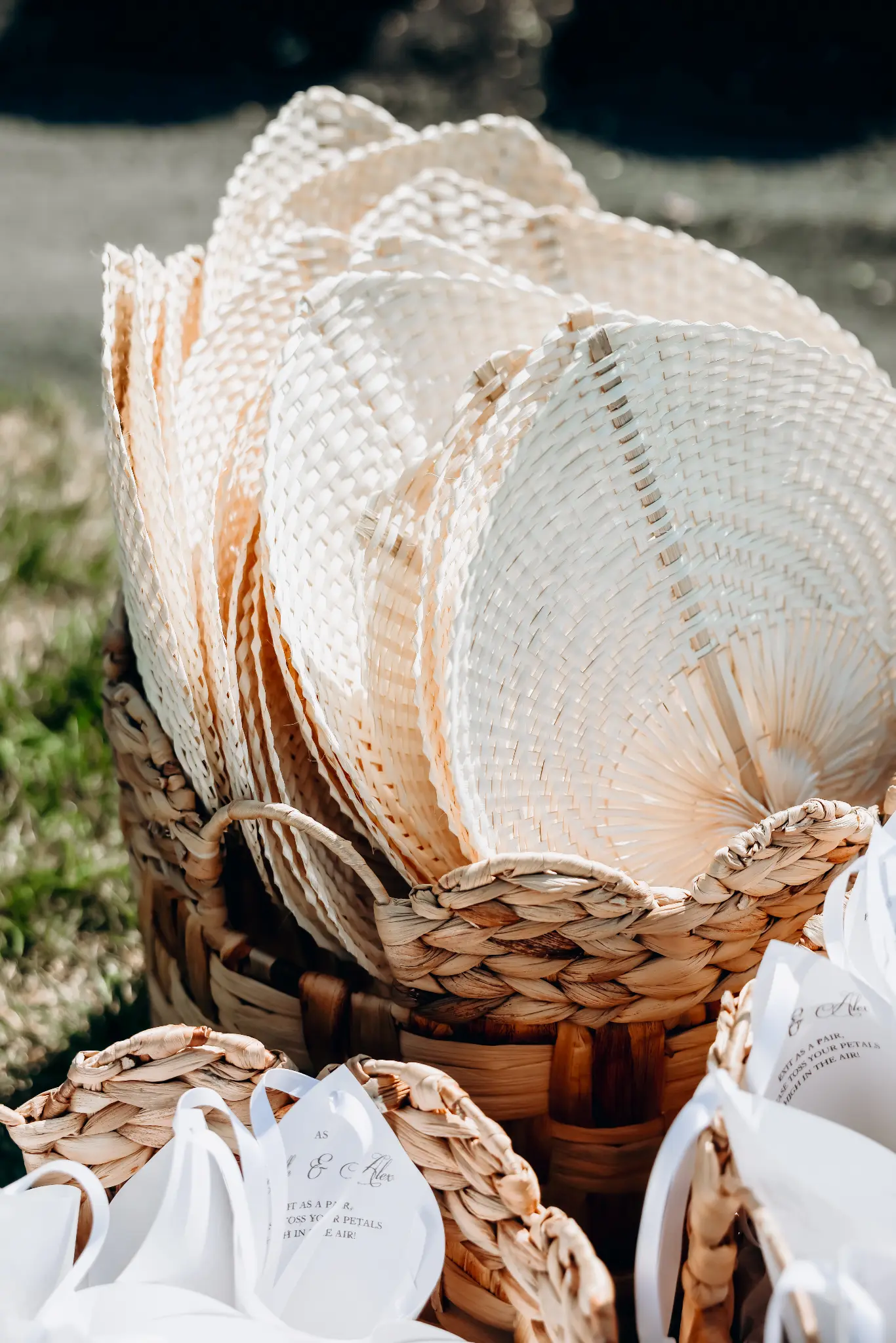 Woven baskets holding white ceremony fans and printed petal-toss bags