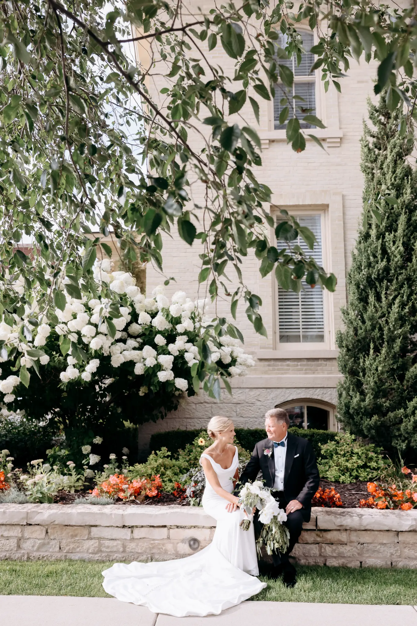 Bride seated in a flowered garden near a historic facade