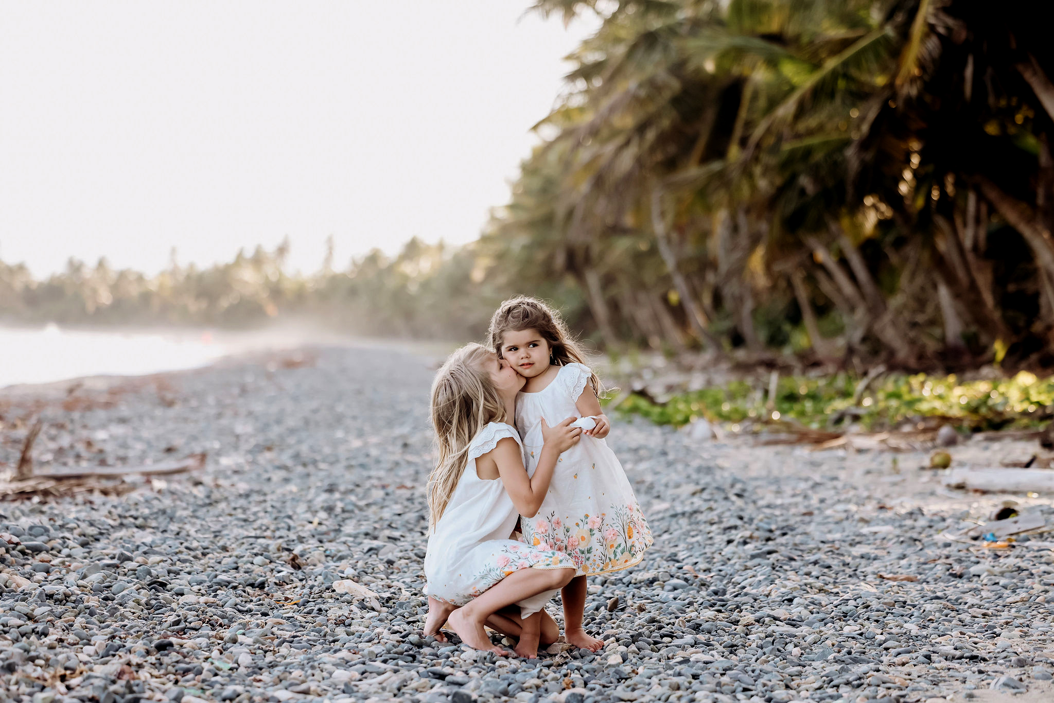 Child sitting beside palm-lined shoreline during a Puerto Rico family session, photographed by Olga Thomas