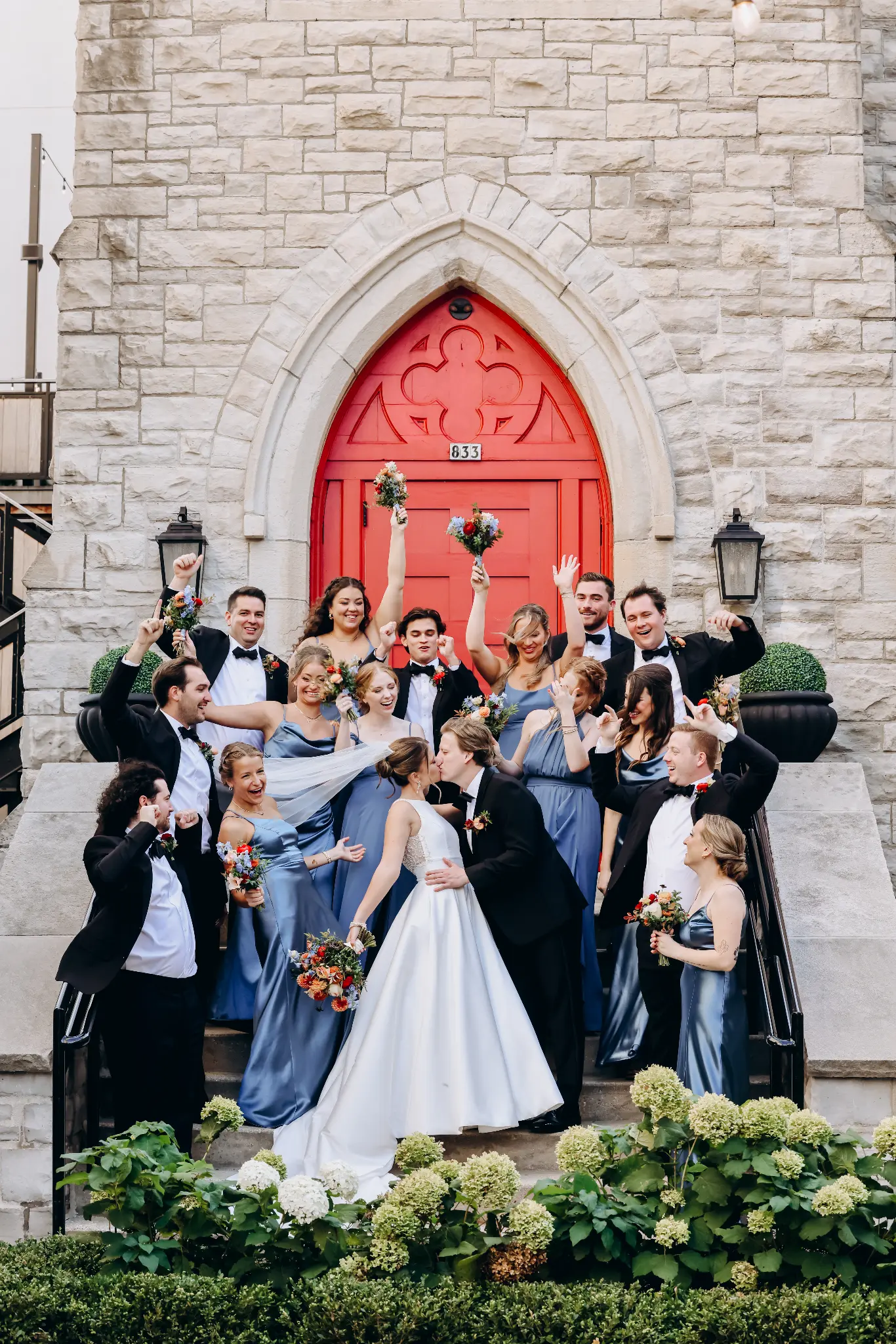 Bride and groom with their wedding party in front of red double doors