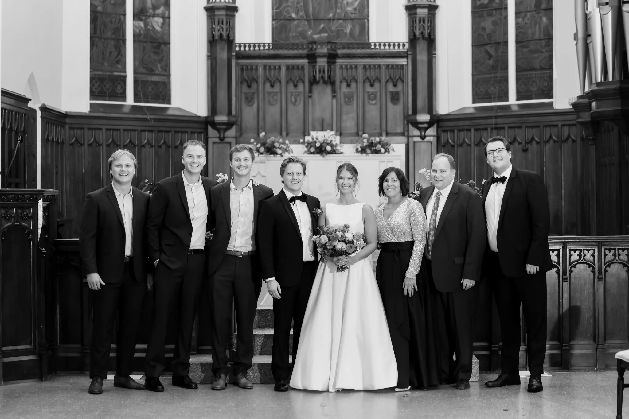 Black-and-white formal family group portrait at the altar inside a traditional church