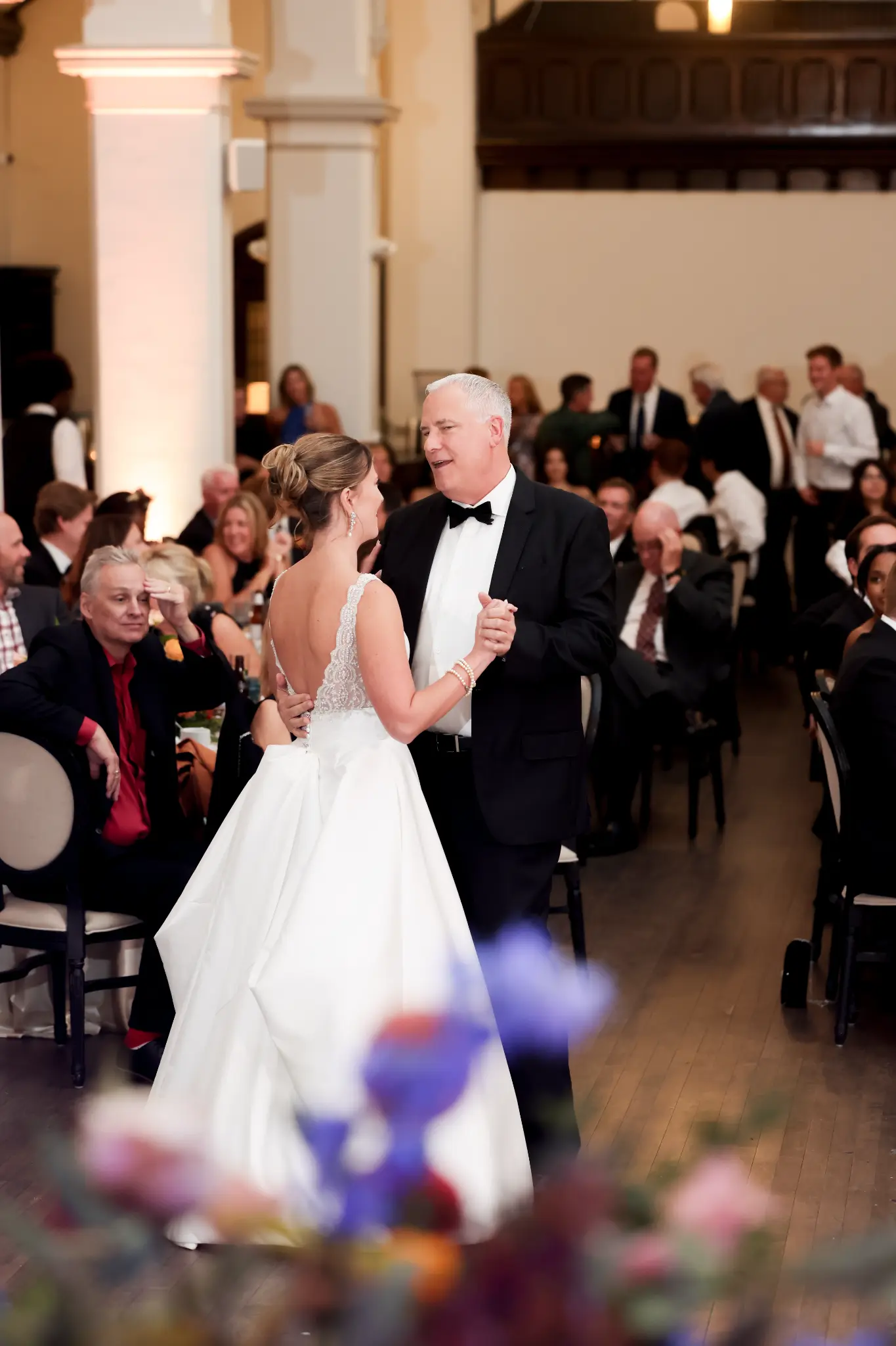 Bride dancing with an older family member in a bright wedding reception room