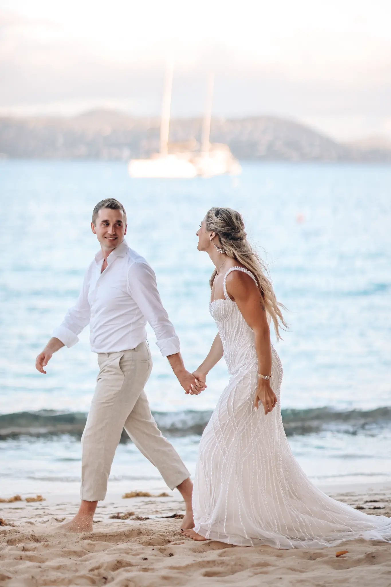 Bride and groom walking hand in hand on a beach