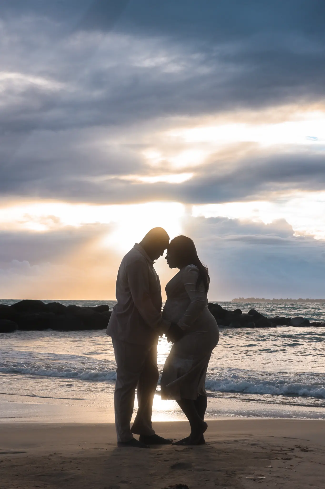 Parent and child silhouetted together by the ocean during a Puerto Rico beach family session, photographed by Olga Thomas