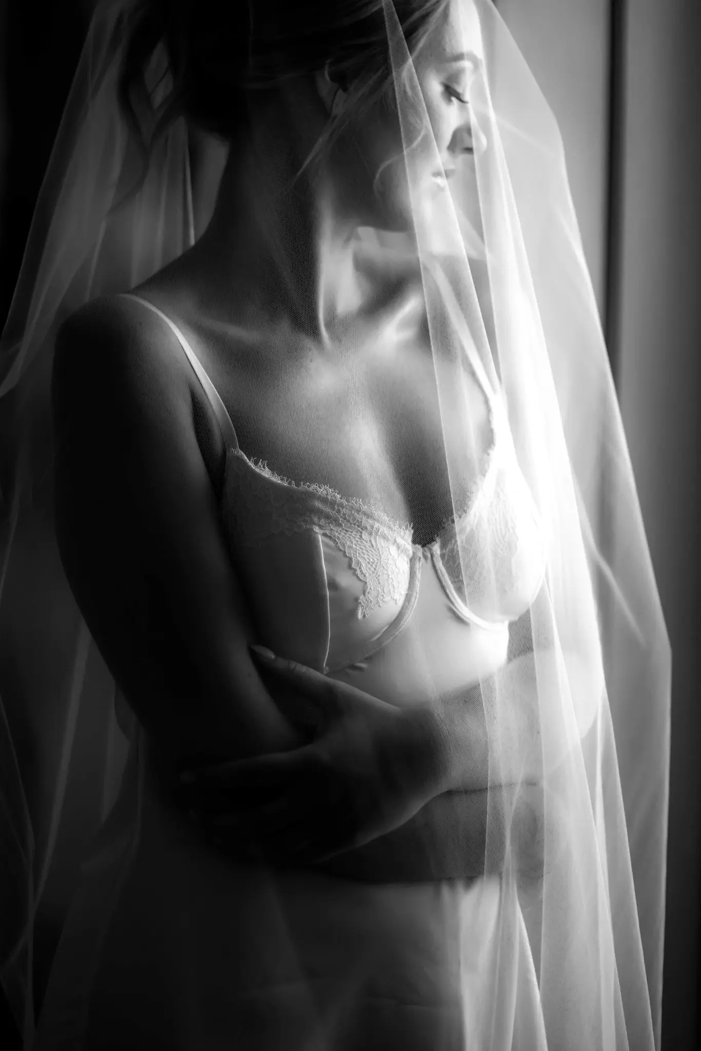 Black-and-white bridal portrait beneath a veil during wedding preparations