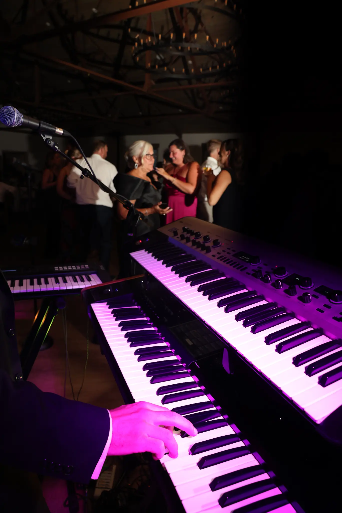 Musician playing a keyboard beneath wedding reception lighting