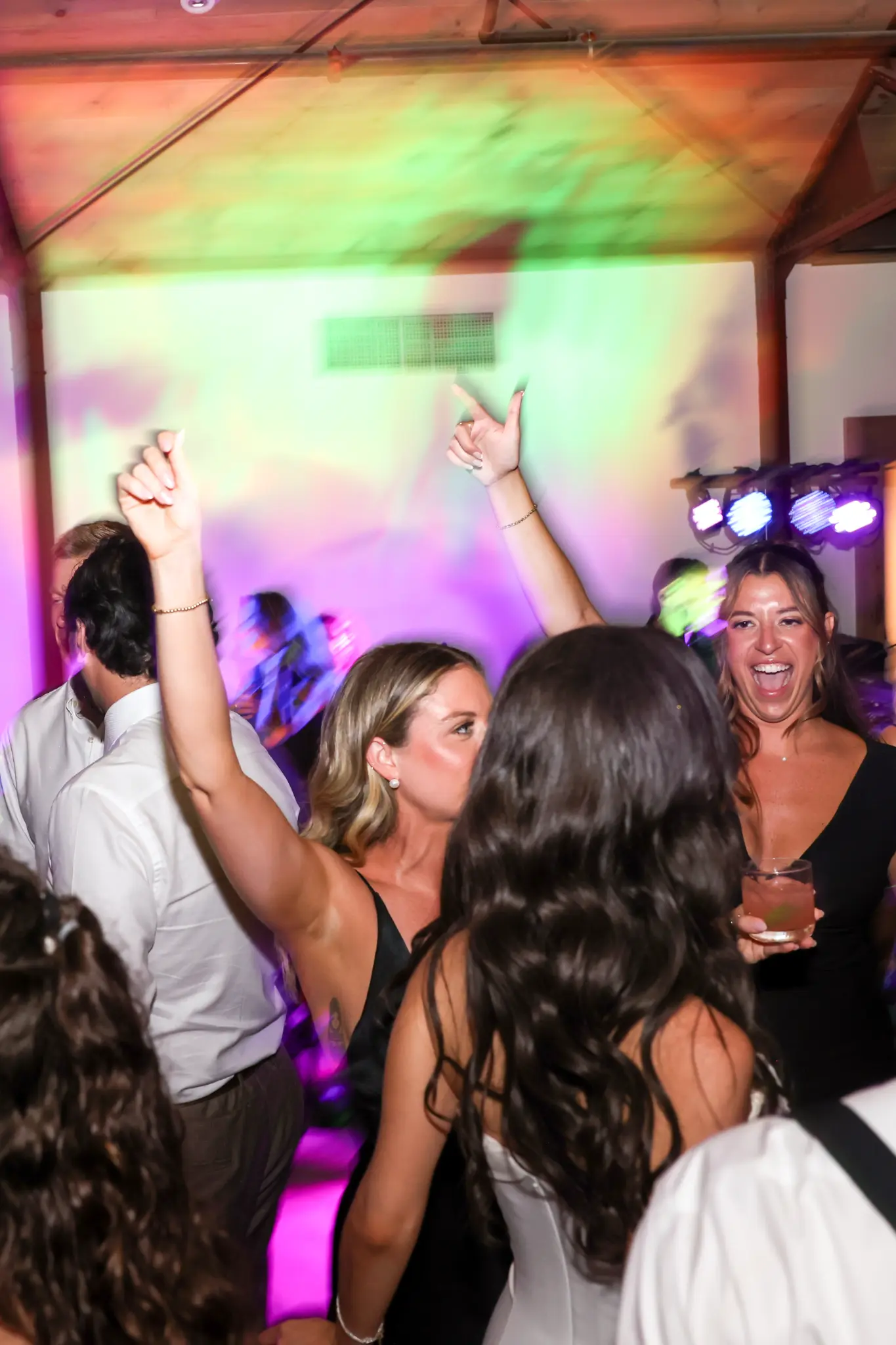 Wedding guests dancing together beneath colorful party lights
