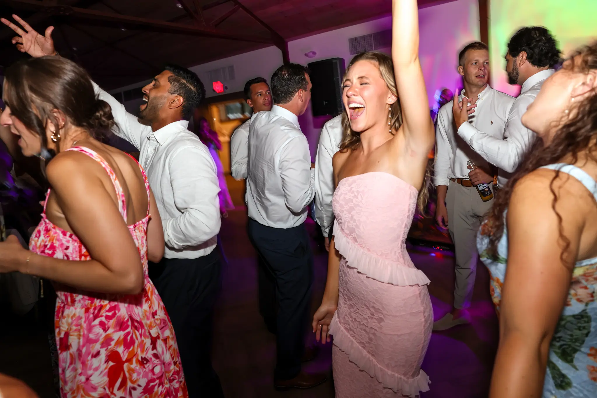Wedding guests dancing beneath colorful party lighting