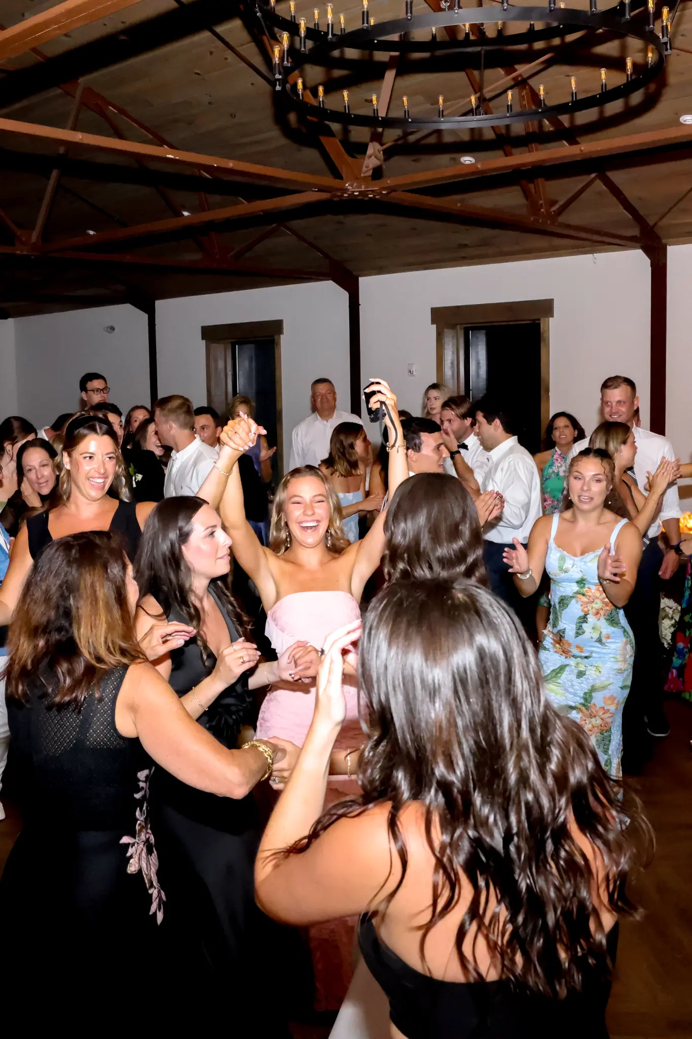 Wedding guests dancing together inside a reception space