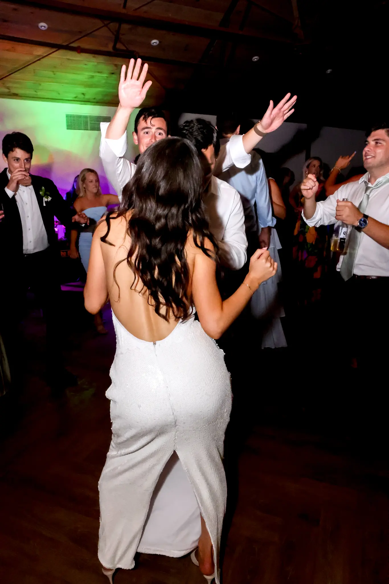 Bride dancing with wedding guests beneath party lighting