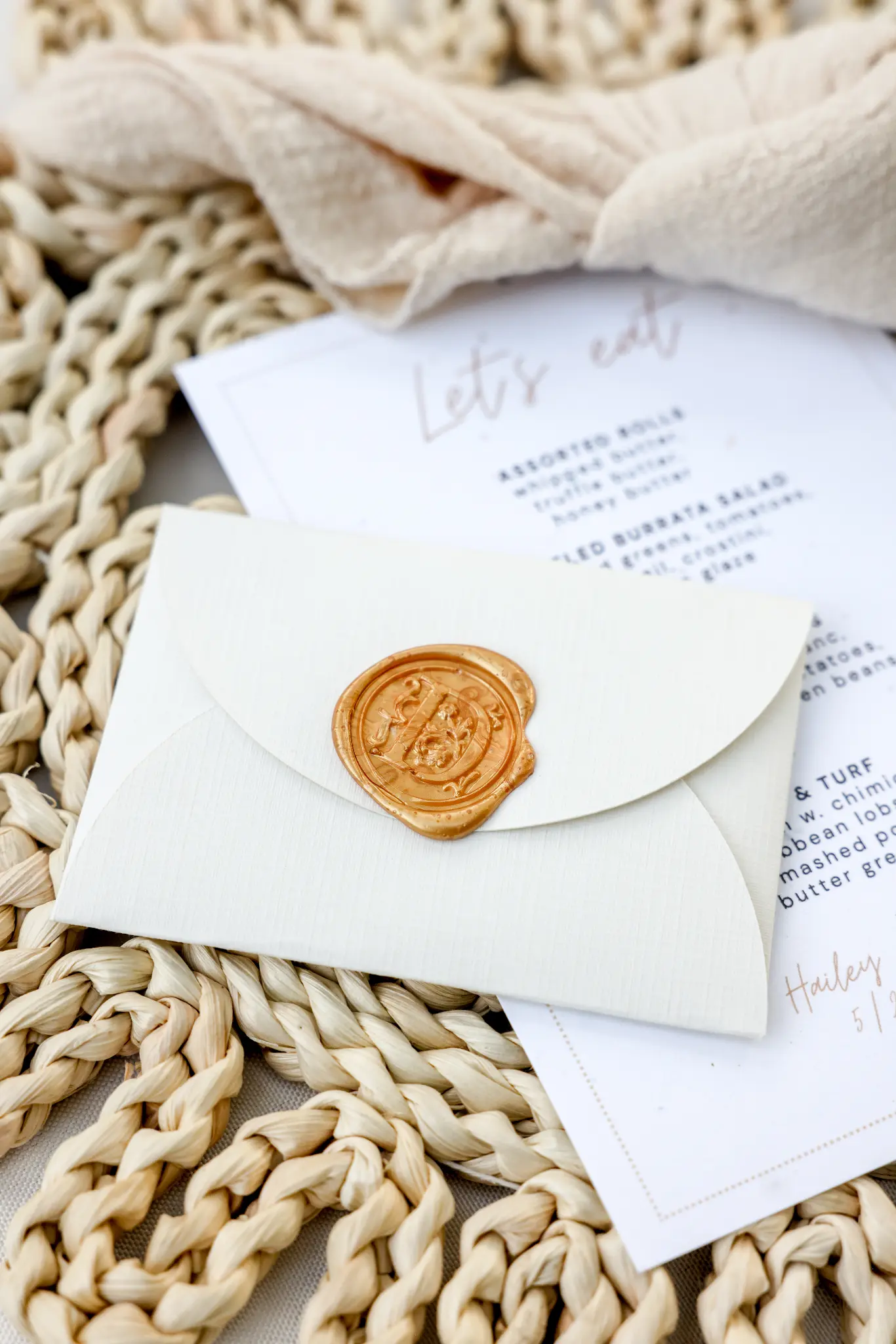 Wedding invitation and wax-sealed envelope on textured fabric