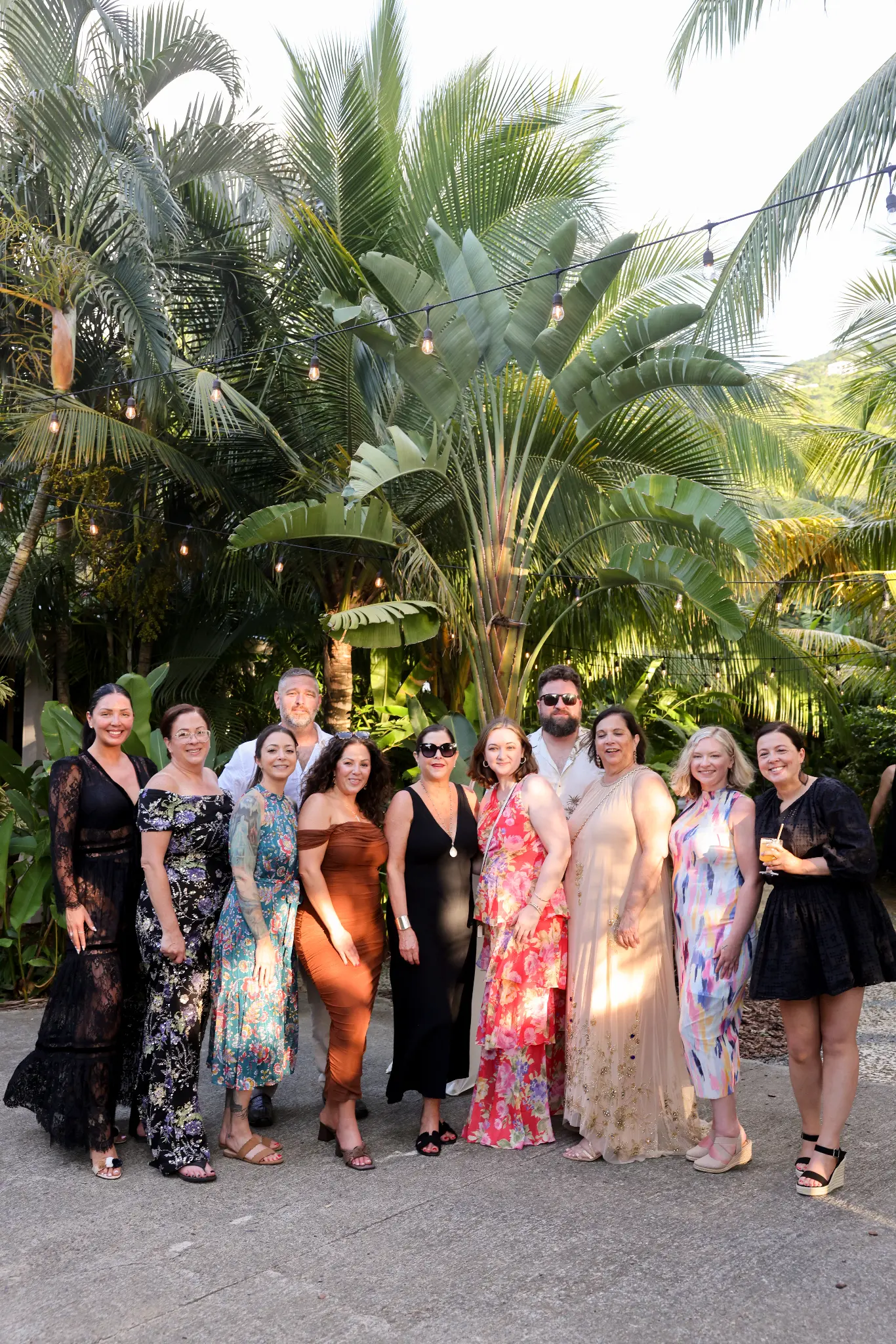 Group portrait of dressed-up wedding guests outdoors among palms