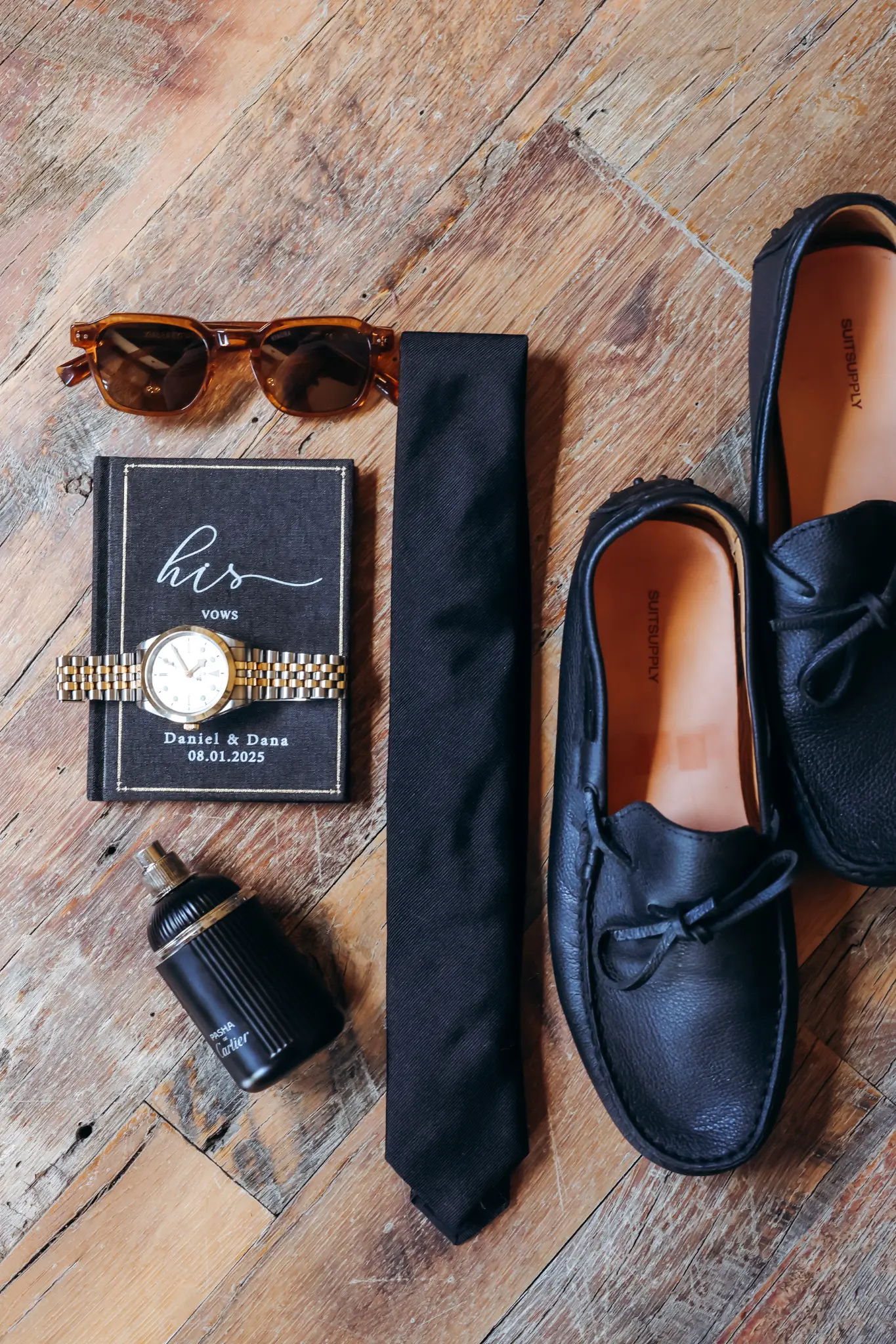 Groom’s wedding-day details with shoes, tie, watch, fragrance, sunglasses, and personalized vows booklet