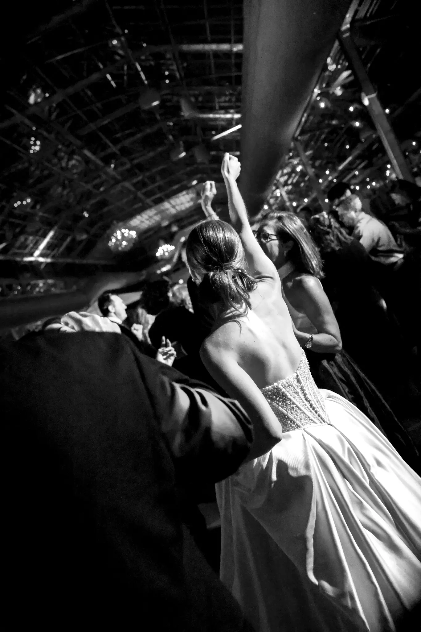Black-and-white elevated view of a bride dancing with wedding guests