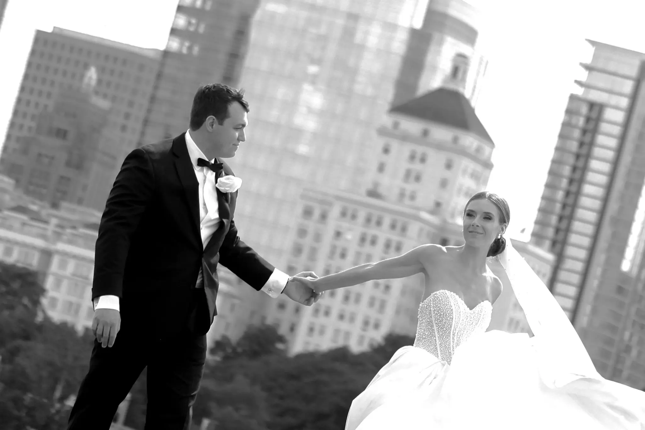 Black-and-white wedding couple portrait on a city street with tall buildings