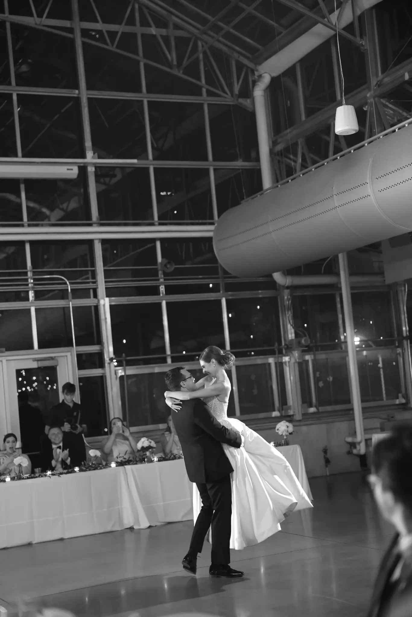 Black-and-white bride and groom dancing together in a large reception room